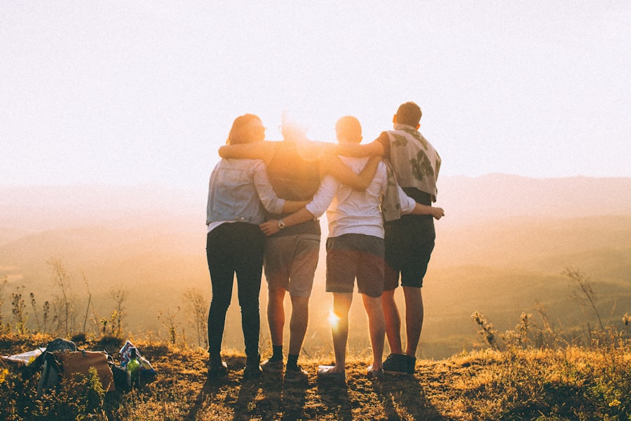 Gruppo di giovani amici abbracciati che guardano il tramonto in collina